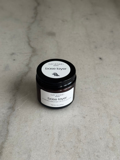 Overhead view of jar of Base Layer by Leopard Goods, 1.6oz, on a marble surface