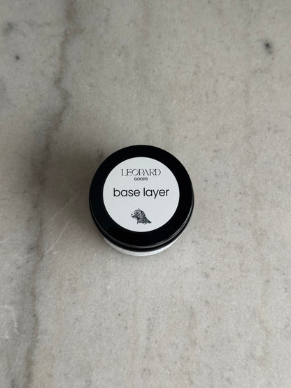 Top label of jar of Base Layer by Leopard Goods, 1.6oz, on a marble surface
