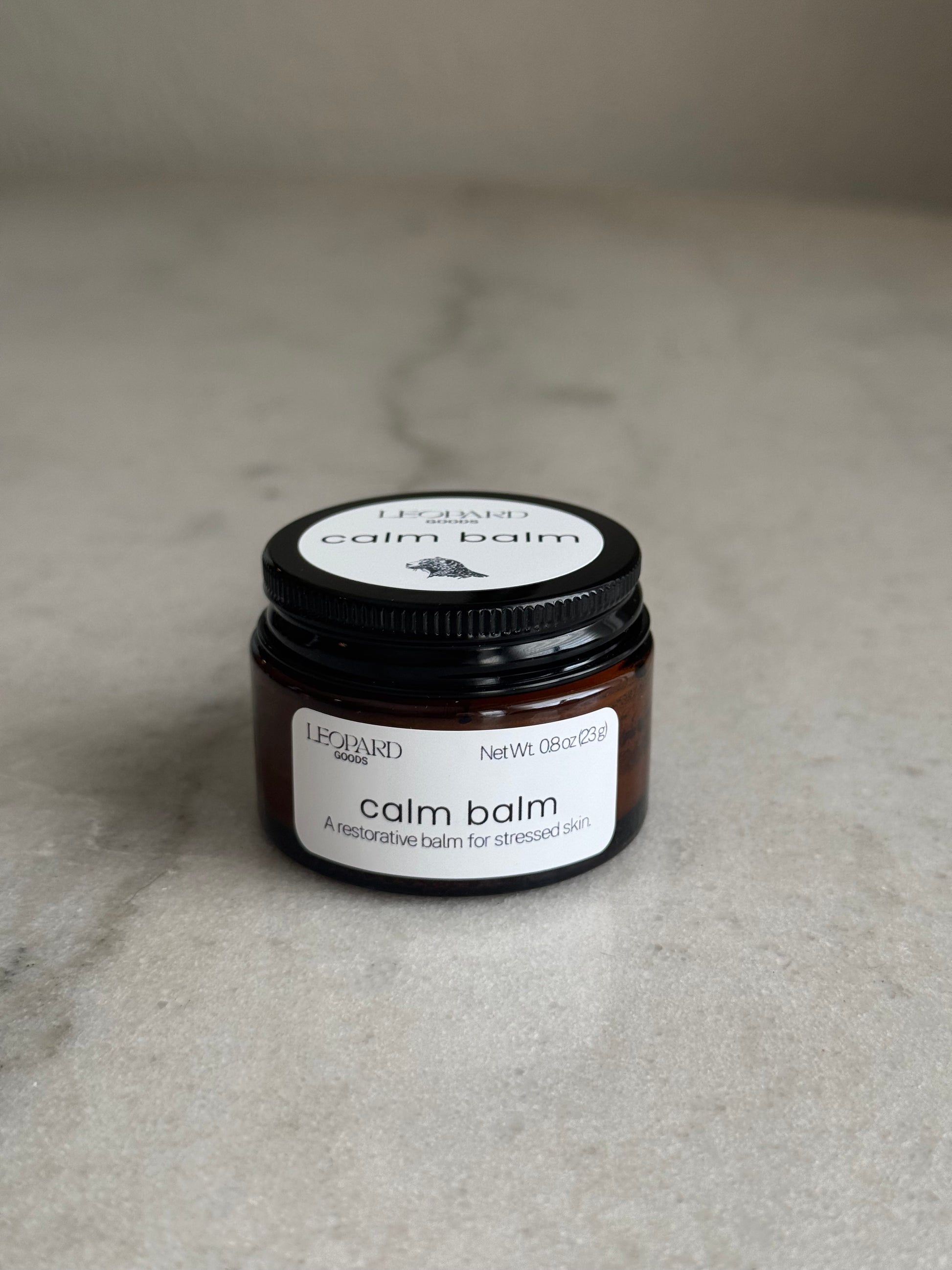 Front label of a 0.8oz jar of Calm Balm by Leopard Wellness on a marble surface