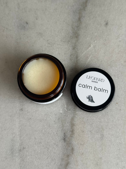 Open 0.8oz jar of Calm Balm by Leopard Wellness on a marble surface