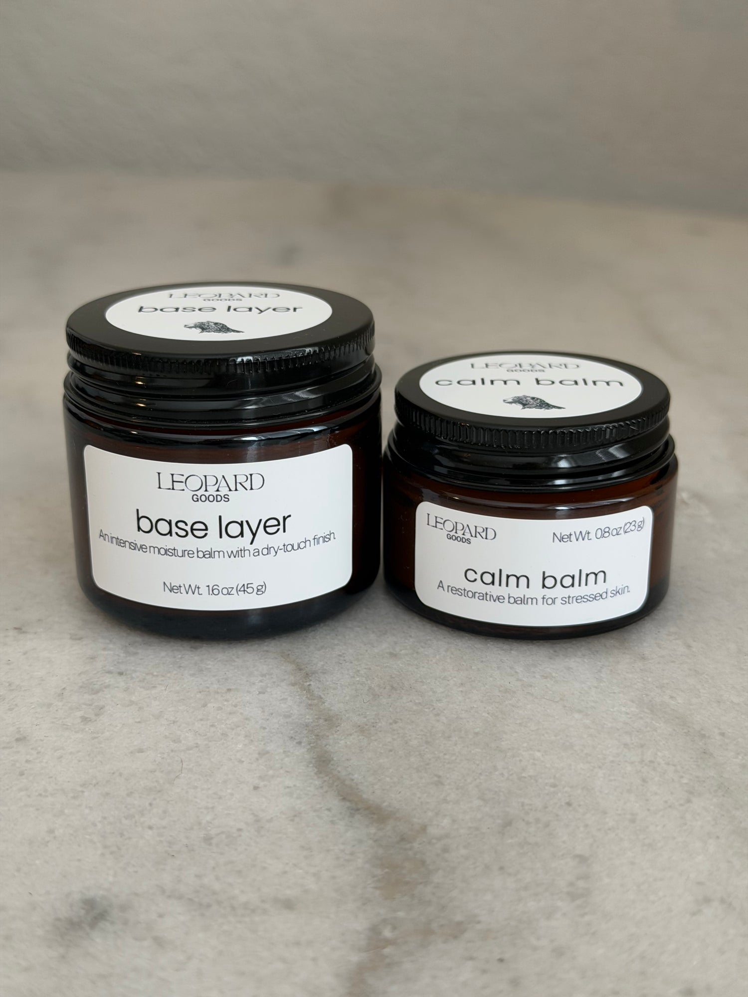 Two jars, one of Calm Balm and one of Base Layer skin balm