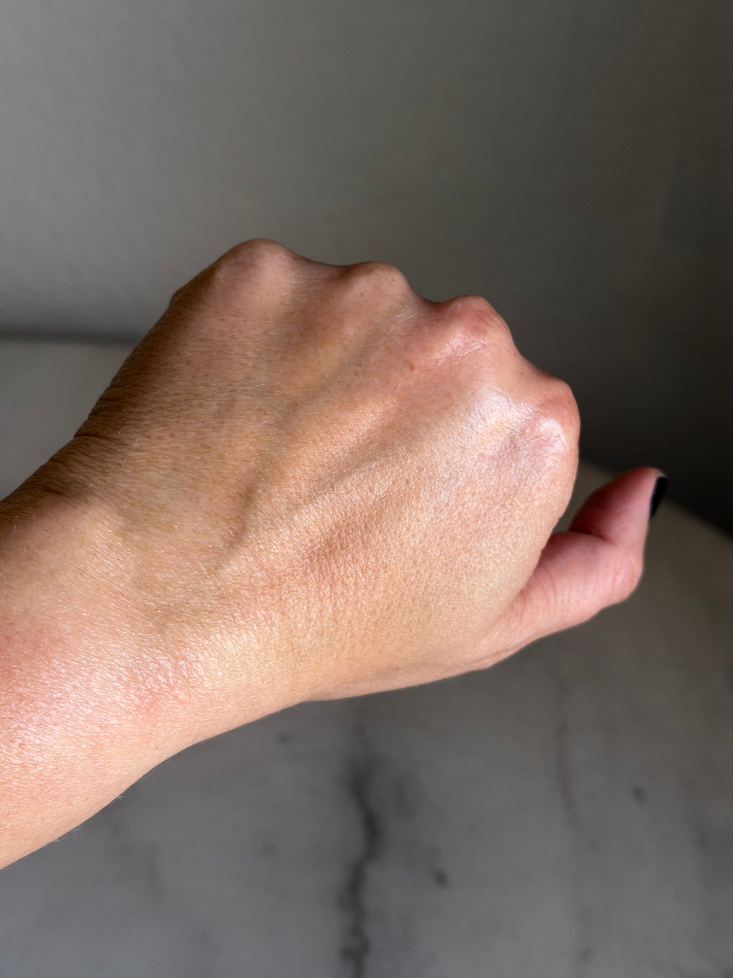 Hand with Calm Balm by Leopard Goods on the back of it, against a gray marble surface 