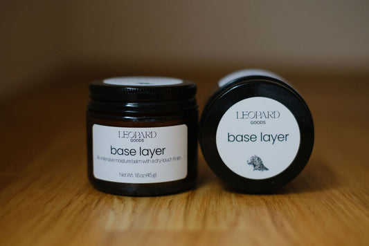 Jars of Base Layer balm on a wooden surface